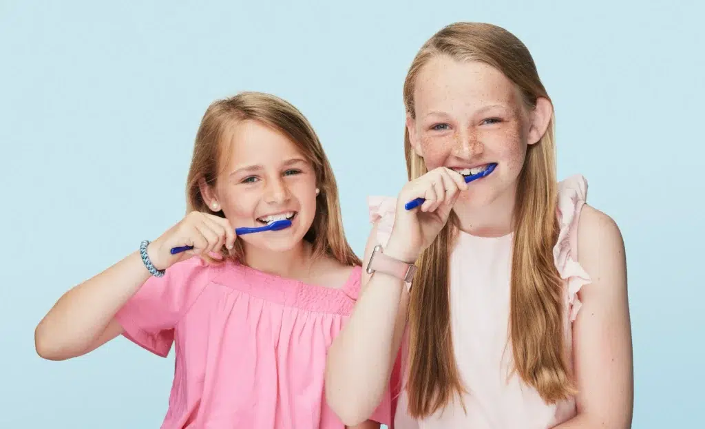 Two girls brushing teeth together