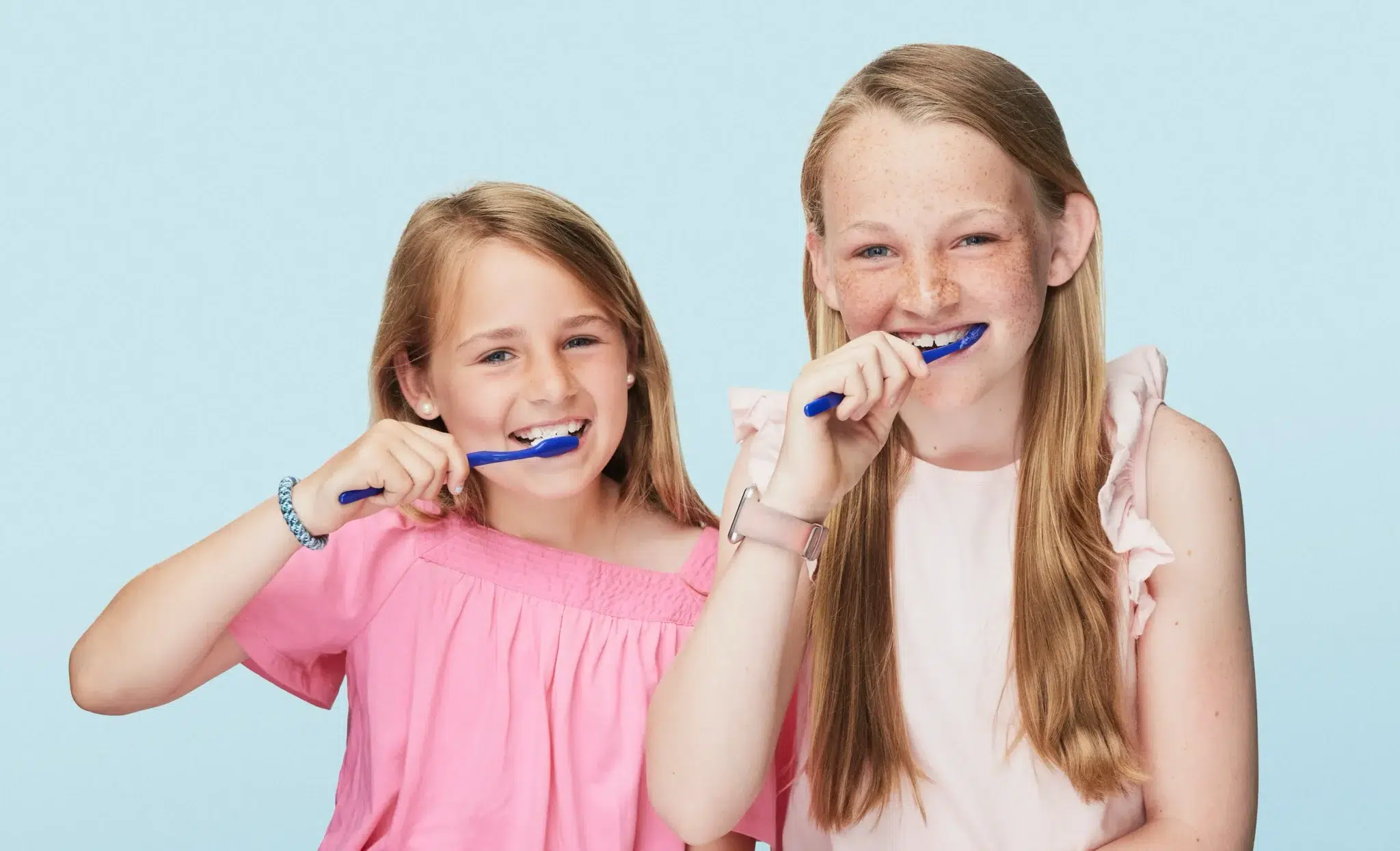 Two girls brushing teeth together