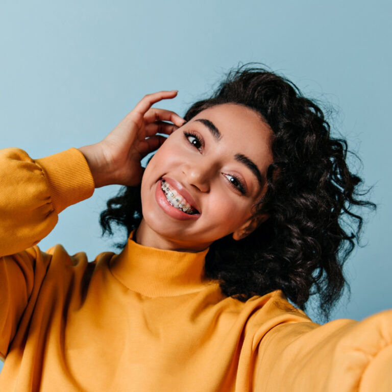 a girl with braces in a yellow shirt